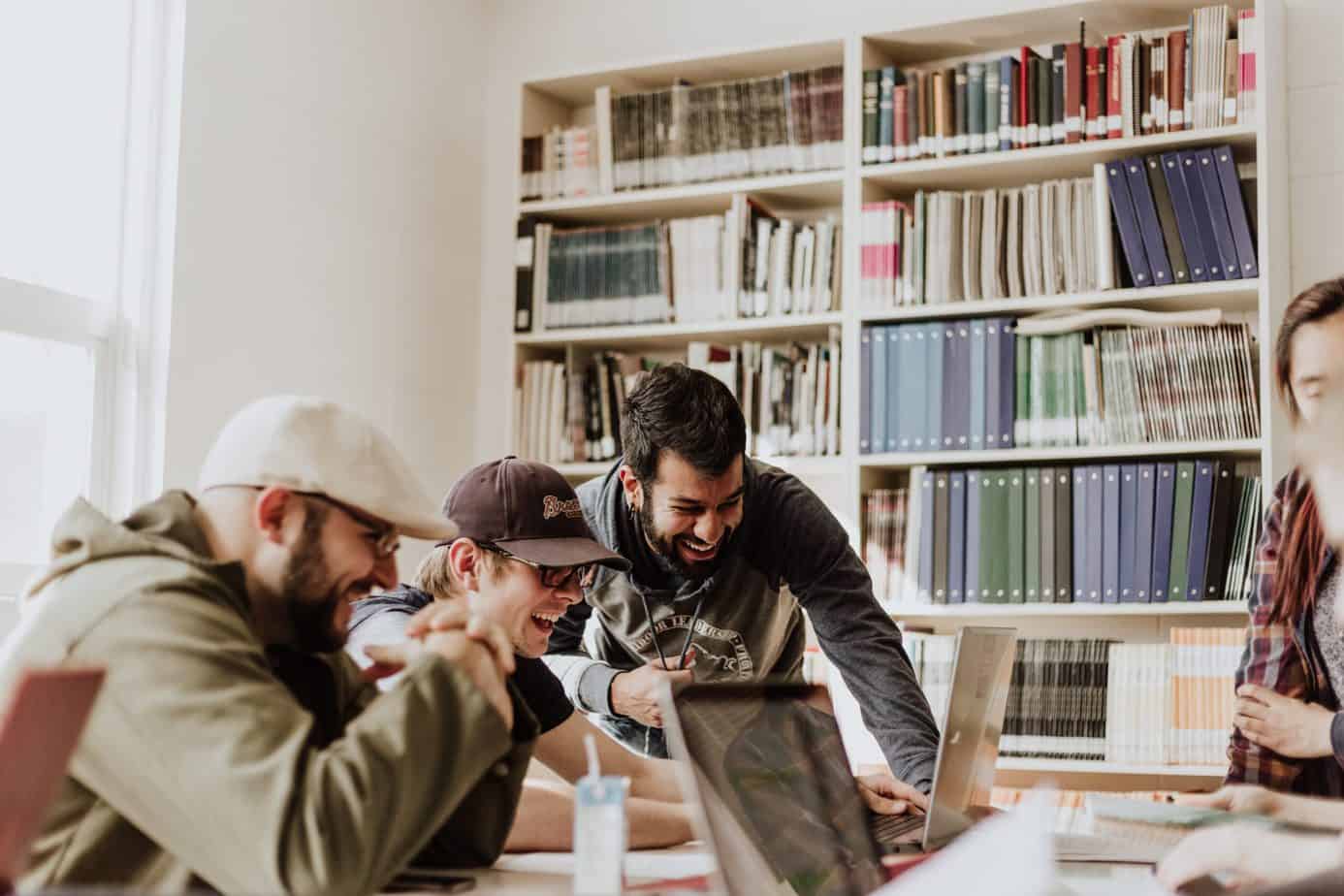 men laughing while looking at laptop