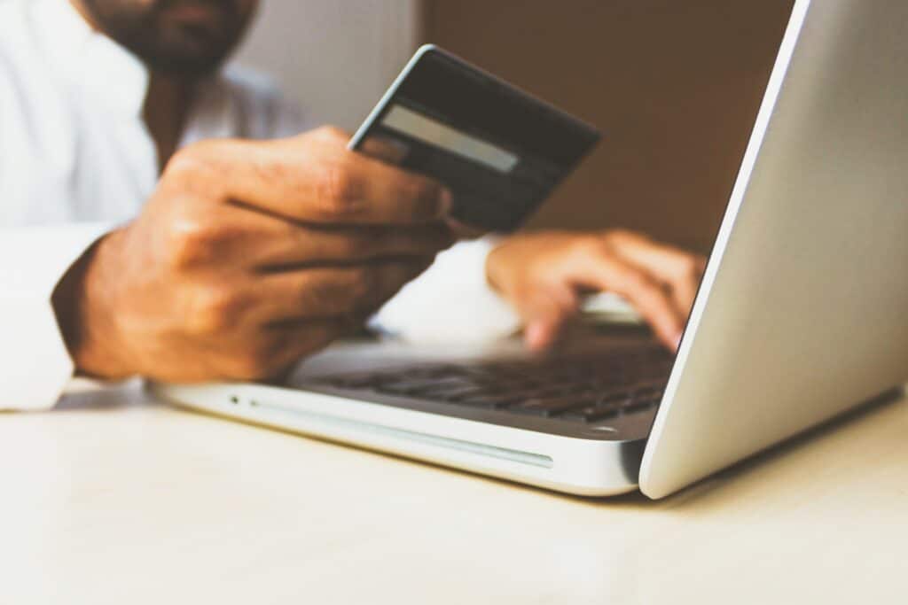 man holding credit card near laptop